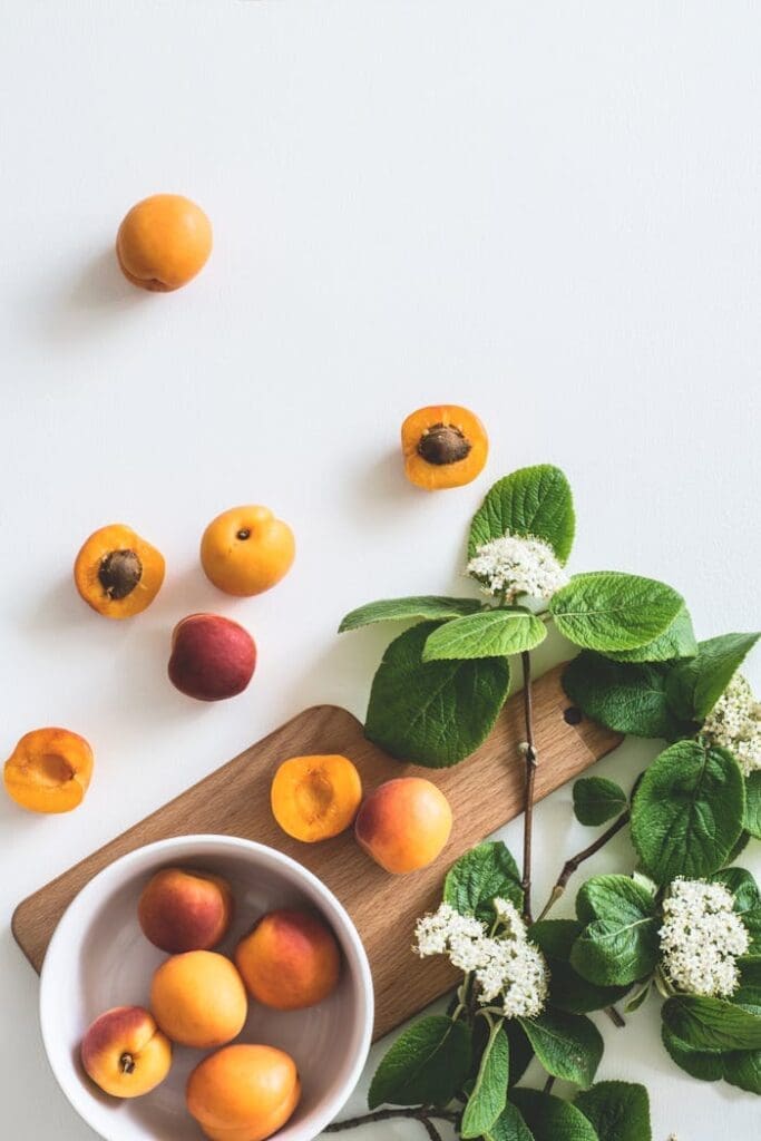 A flat lay of fresh apricots and blossoms on a board showcasing summer freshness.